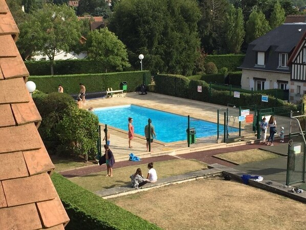 A swimming pool surrounded by a fence, with people around it.