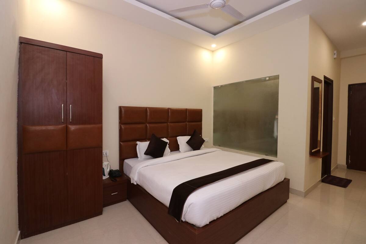 A bedroom with a large bed, a wardrobe, a mirror, and a ceiling fan.