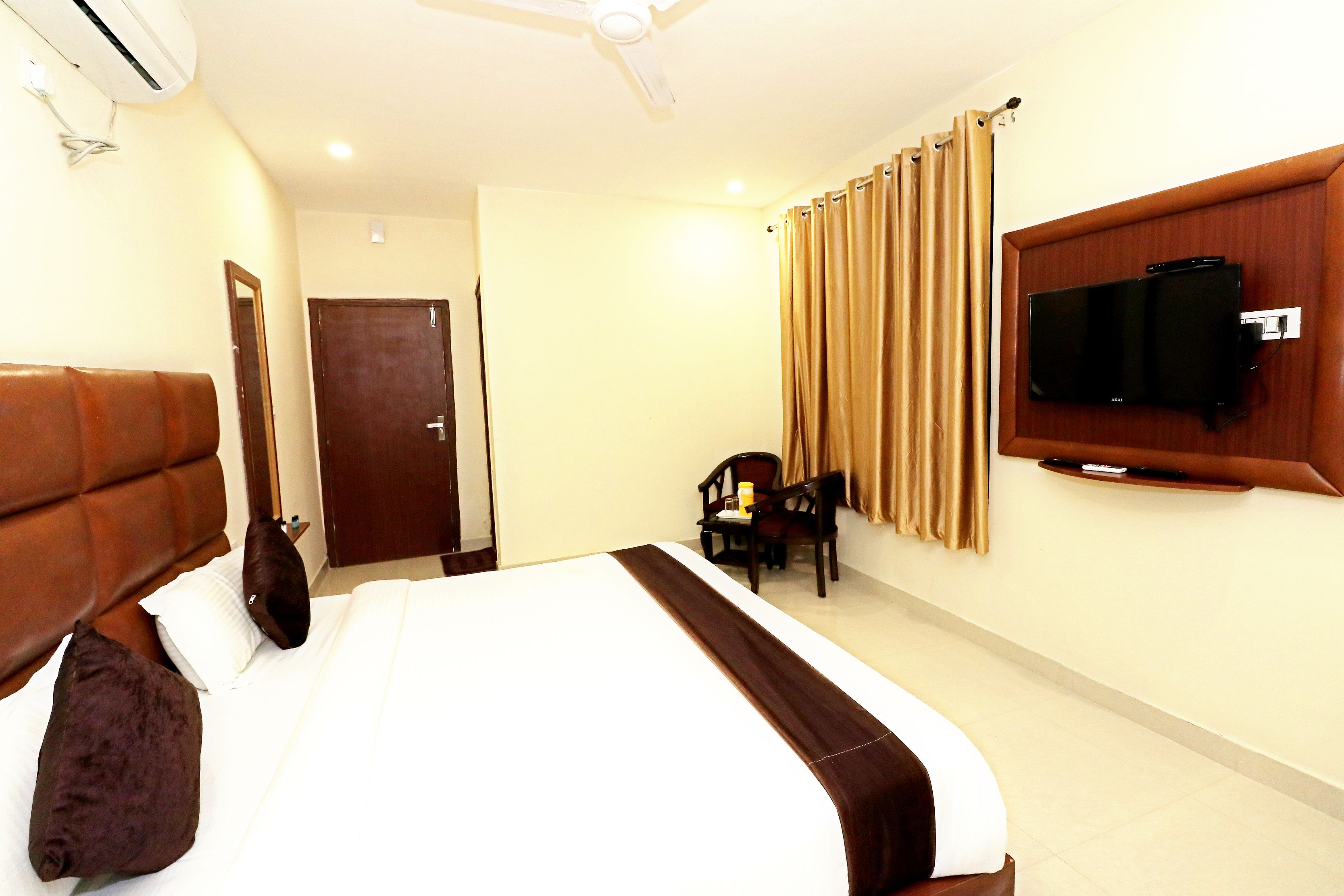 Una habitación de hotel con una cama grande, un televisor en la pared y una puerta que da a otra habitación.