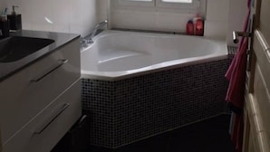 Un baño con bañera, lavamanos y ventana.