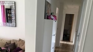 Un pasillo con un sofá color beige, un armario blanco y un espejo con marco decorativo.