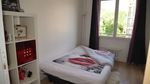 Un dormitorio con cama, armario y ventana con cortinas.