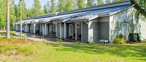 Una hilera de cabañas de un piso con porches anexos, rodeadas de césped y árboles.