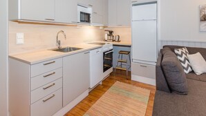 A compact kitchenette with a microwave, stove, sink, and a small refrigerator.
