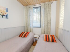 Una habitación con dos camas individuales, una mesita y una ventana con cortinas.