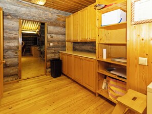 Un intérieur en bois comprenant un espace cuisine, avec des placards, un plan de travail et une poubelle.