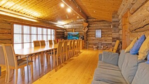 A log cabin interior with a dining area, wooden floors, and a sofa.
