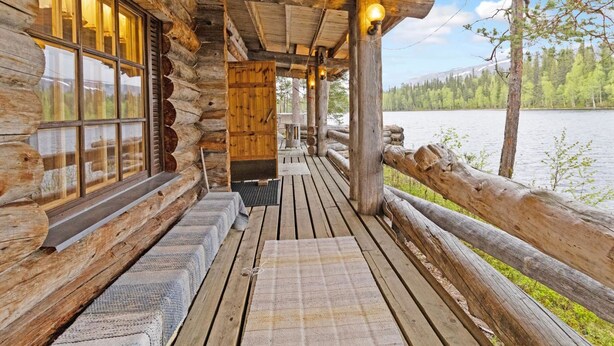 A log cabin with a wooden deck overlooking a lake.