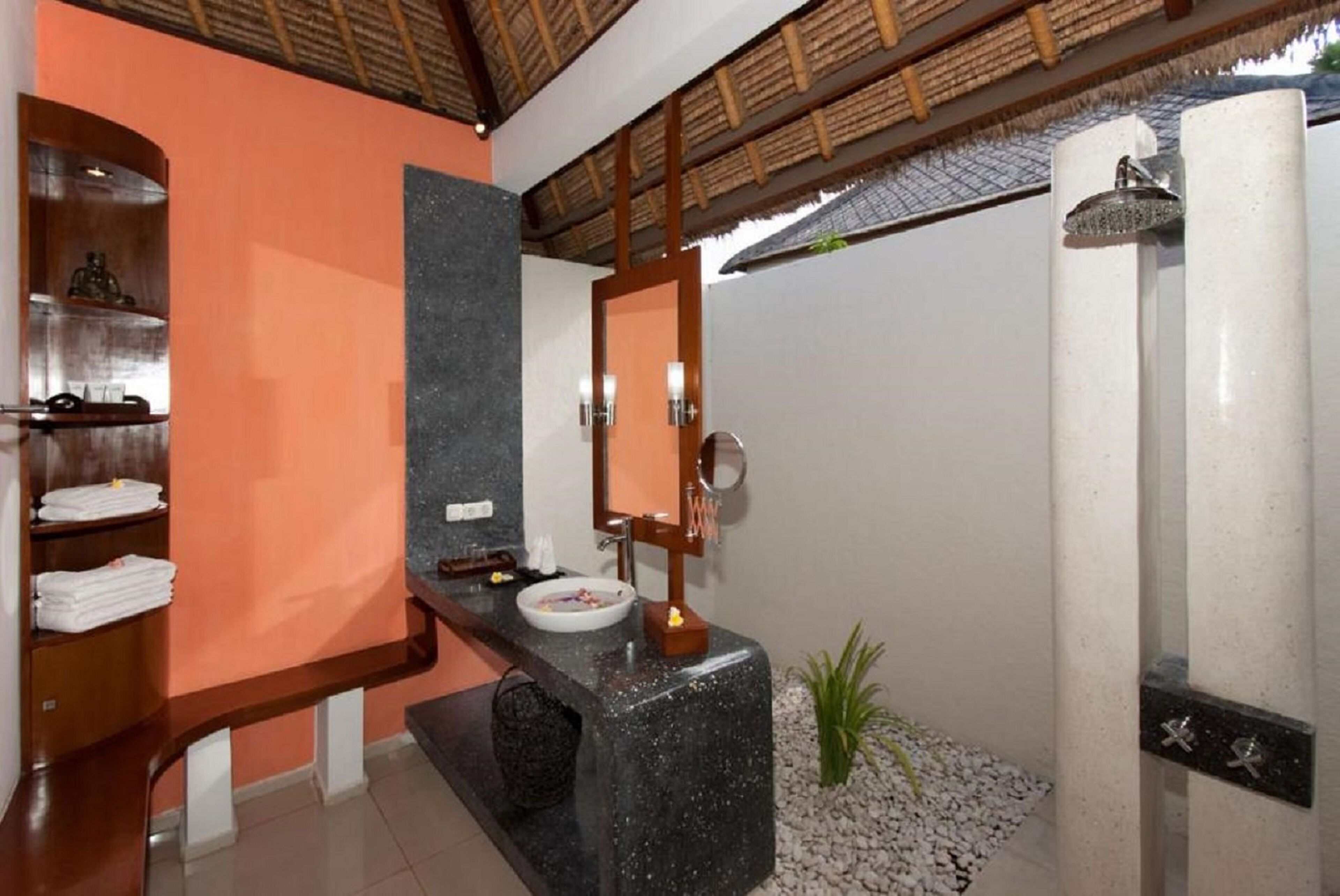 Un baño moderno con tocador curvo, un espejo grande, lavabo integrado y zona de ducha.