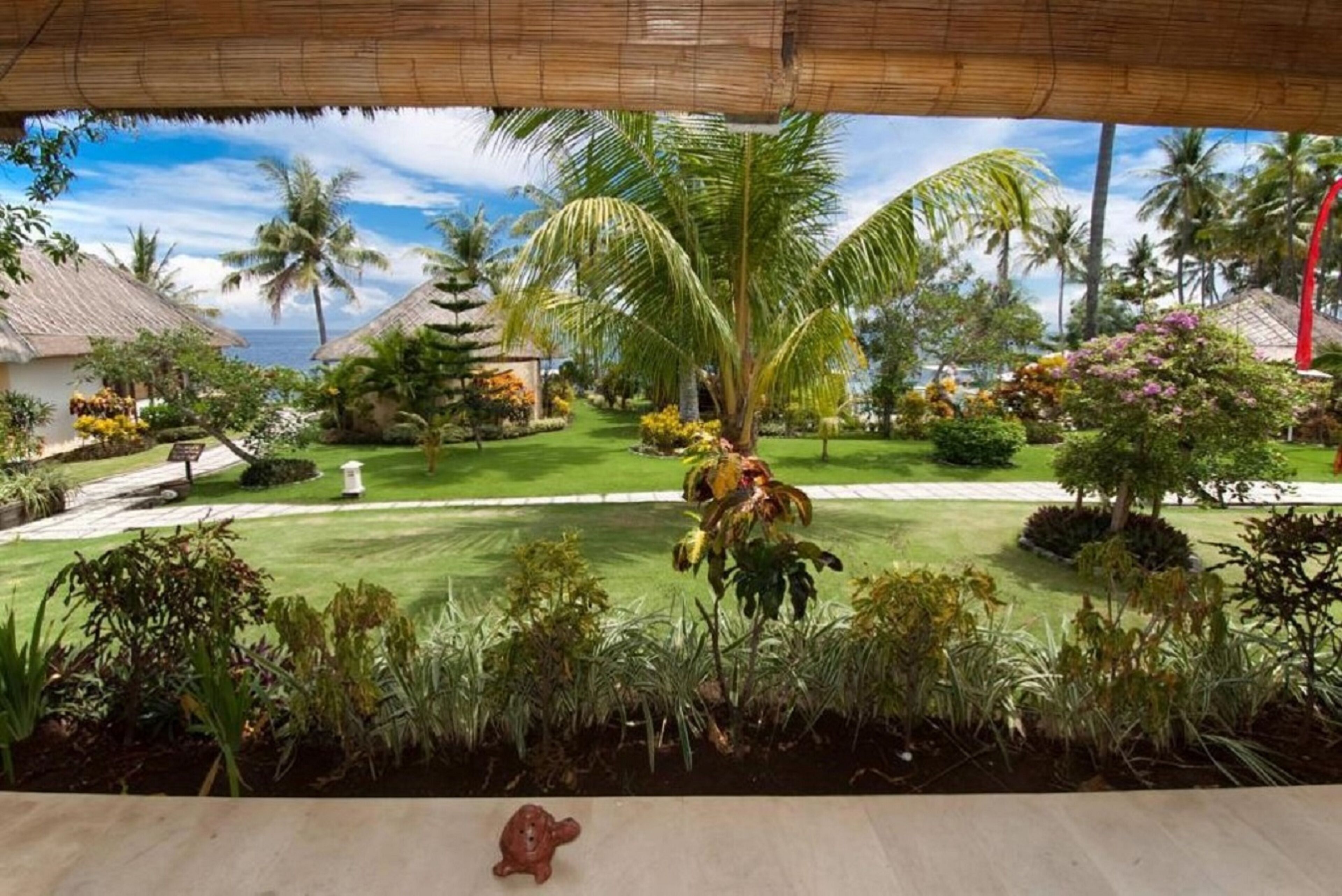 Un jardin tropical avec des palmiers, un sentier et une petite statue de tortue.