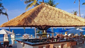 A beachside bar with a thatched roof, outdoor seating, and a view of the ocean. - Siddhartha Oceanfront Resort & Spa Bali (Kubu)