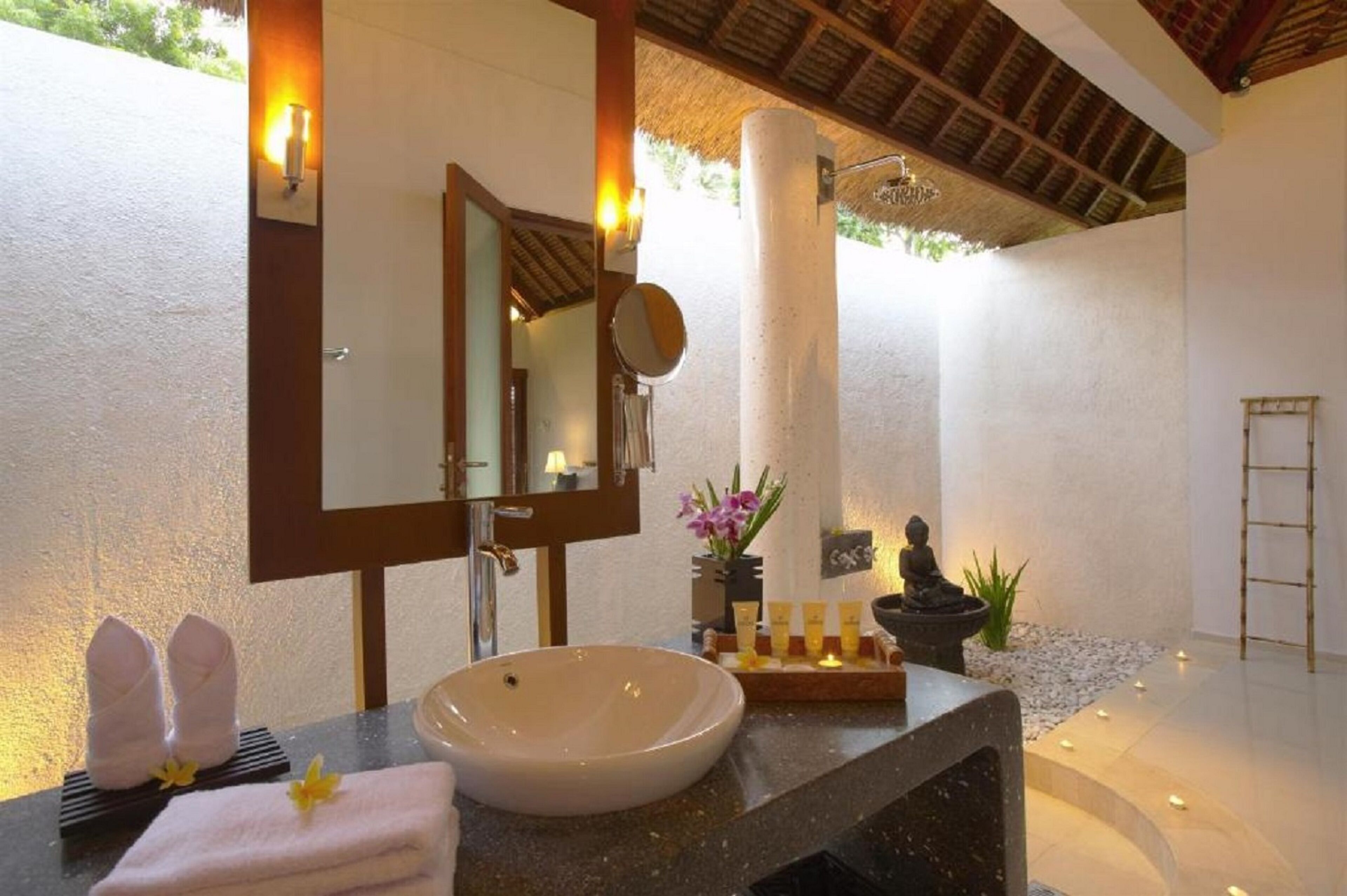 A bathroom with a large mirror, a sink, and a towel rack.