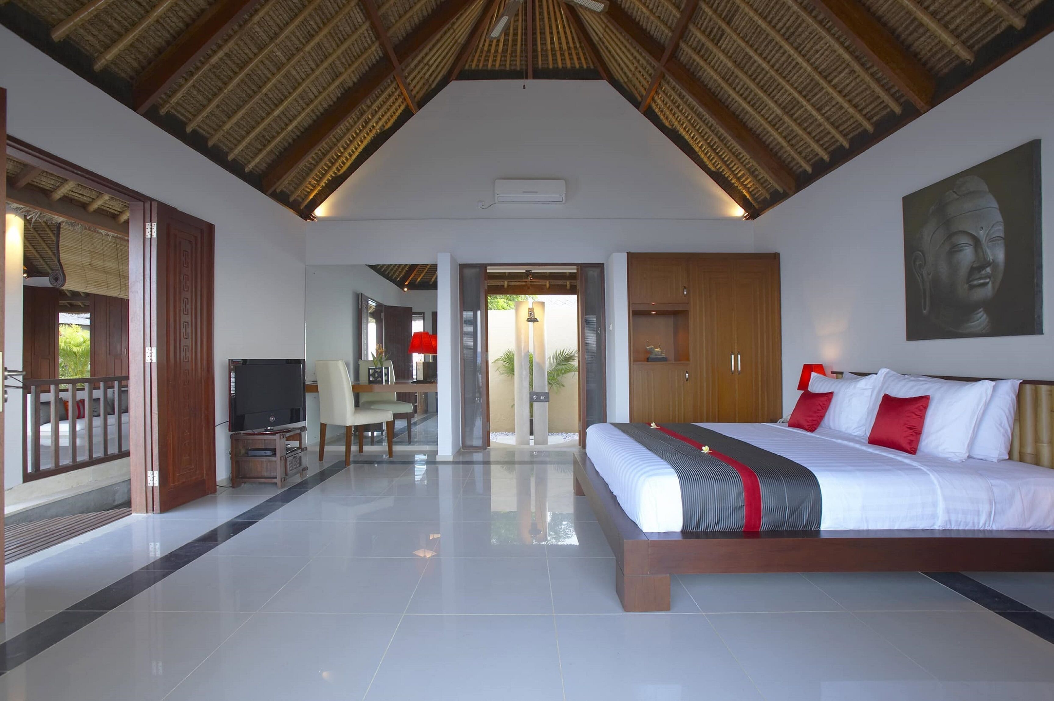 A modern hotel room with a large bed, a television, and a dining area with a table and chairs.