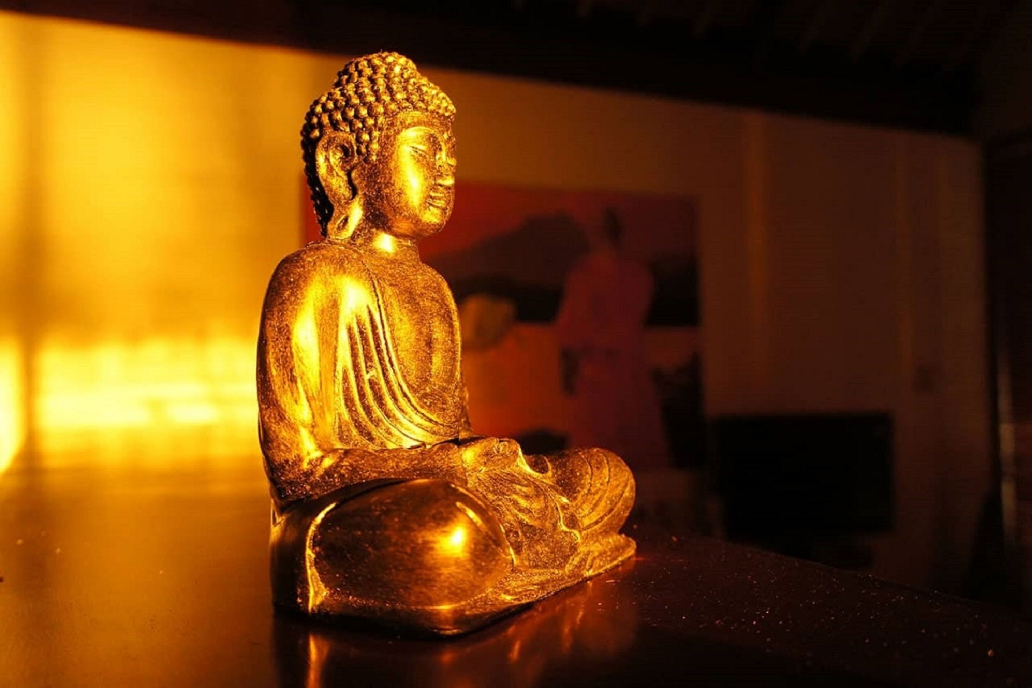 Estátua dourada de Buda num espaço pouco iluminado.