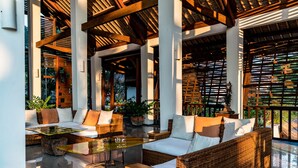 A spacious indoor area with wicker furniture, a glass coffee table, and potted plants. - Siddhartha Oceanfront Resort & Spa Bali (Kubu)