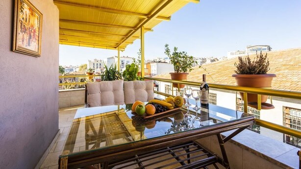 A balcony with a glass table, potted plants, and a sofa. - The First Ottoman Suites (Istanbul)