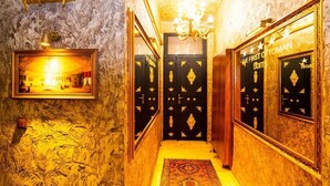A hallway with ornate black doors, a chandelier, and a framed picture on the wall. - The First Ottoman Suites (Istanbul)