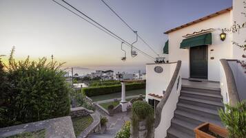 Un edificio blanco con un toldo verde, una escalera y vistas al paisaje.