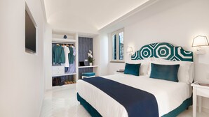 A bedroom with a large bed, a wardrobe, a vanity, and a window. - Relais Caposcuro (Anacapri)