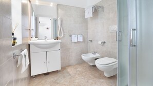 A modern bathroom with a sink, bidet, toilet, and glass shower enclosure. - Relais Caposcuro (Anacapri)