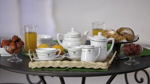 A breakfast setup with white ceramic dishes, a pitcher, glasses, and pastries on a round table. - Relais Caposcuro (Anacapri)