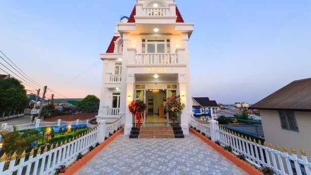 A white building with a red roof and a sign that reads "HOSTEL".