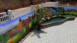 A courtyard with a mural, a small pool, and a white fence.