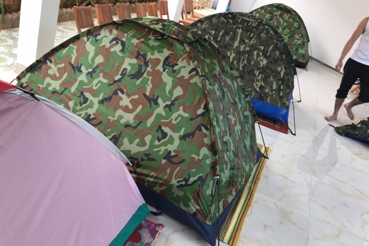 Une pièce contenant plusieurs tentes, dont une avec un motif de camouflage et une autre avec une couleur rose à l’extérieur.