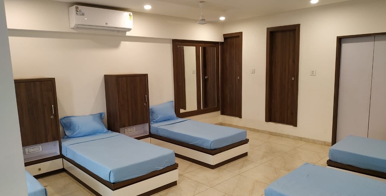 Un dormitorio con tres camas individuales, armarios de madera y un equipo de aire acondicionado.