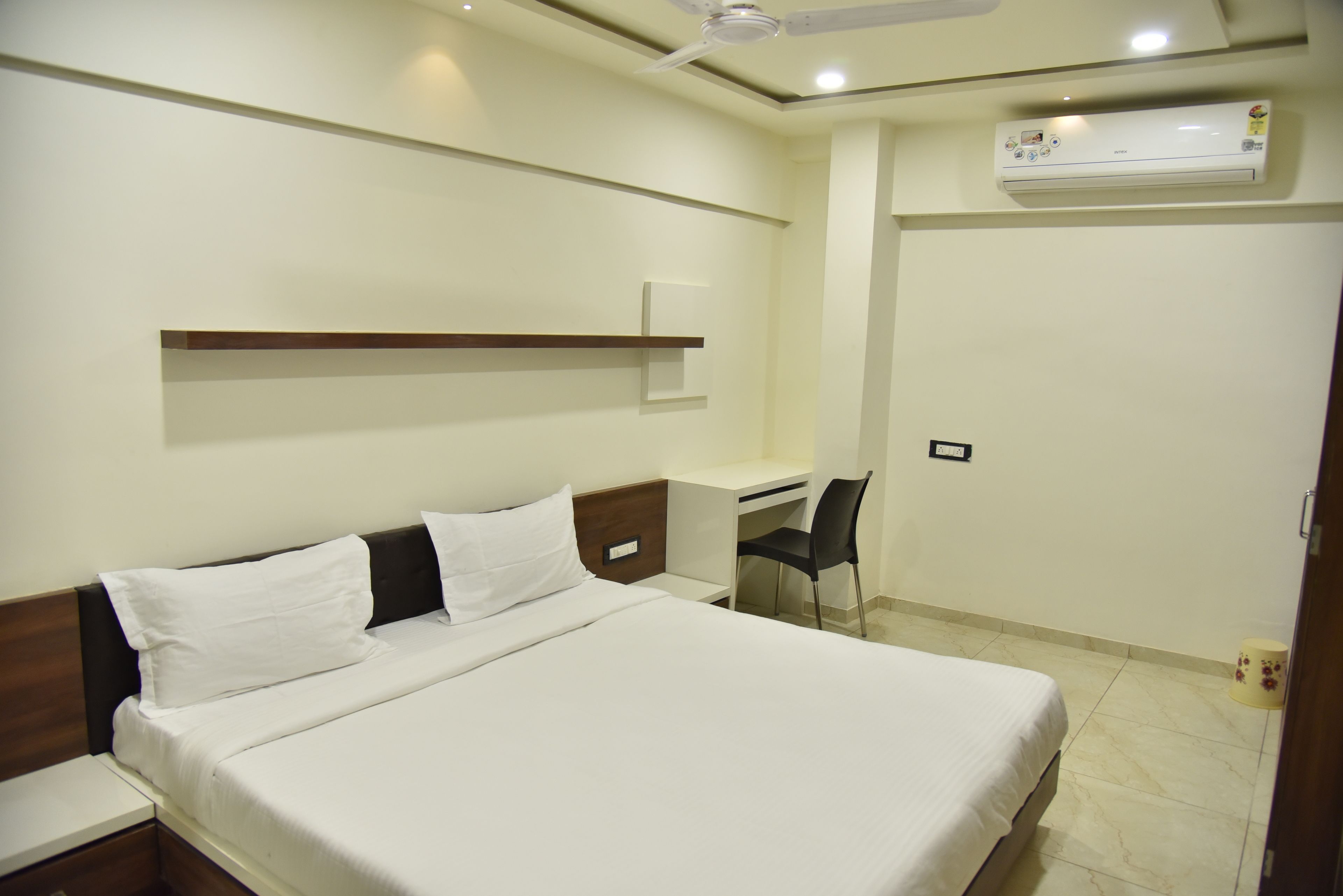 Quarto de hotel com cama, escrivaninha, cadeira e ar condicionado.