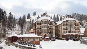 Um hotel com vários andares, um teleférico e um pequeno edifício com a inscrição 'PIZZA' em primeiro plano.