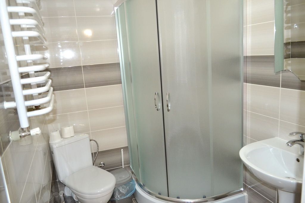 Un baño con inodoro, lavamanos y ducha con mampara de vidrio.