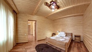 Quarto com painéis de madeira, uma cama, uma mesa de cabeceira e uma porta que dá para outro espaço.