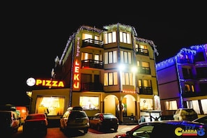 A multi-story building with a 'PIZZA' sign, balconies, and a 'LEKU' sign. - Villa Leku Spa Resort (Bukovel)