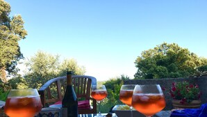 Zona pranzo all'aperto con tavolo apparecchiato per quattro, inclusi bicchieri da vino, piatti e una bottiglia.