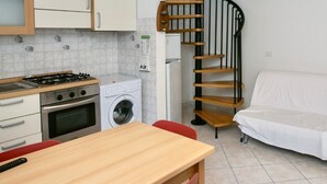 A compact kitchen with a stove, oven, washing machine, and a wooden table. - N099 - Numana, delightful apartment 150mt from the sea (Numana)
