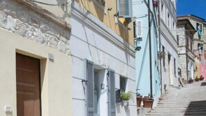 A narrow street with a white table and red chair outside a building with a brown door and shutters. - N099 - Numana, delightful apartment 150mt from the sea (Numana)