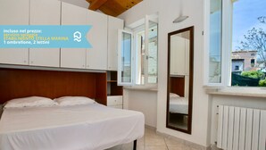 A bedroom with a bed, a large window, a mirror, and a view of the outside. - N099 - Numana, delightful apartment 150mt from the sea (Numana)