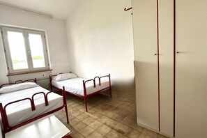 A room with two beds, a window, and a wardrobe. - M079 - Marcelli, seafront three-room apartment in a residence with swimming pool (Marcelli)