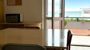 Una habitación con una mesa de madera, microondas y vista al océano a través de un ventanal.