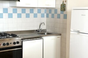 A kitchen with a gas stove, sink, and white cabinets. - M079 - Marcelli, seafront three-room apartment in a residence with swimming pool (Marcelli)