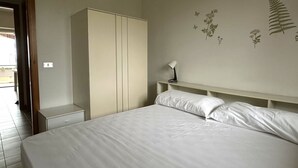 Un dormitorio con cama, armario, mesita de noche y lámpara de pared.
