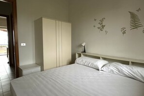 A bedroom with a bed, a wardrobe, a nightstand, and a wall-mounted lamp. - M079 - Marcelli, seafront three-room apartment in a residence with swimming pool (Marcelli)