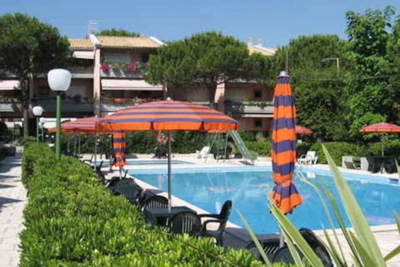 A pool area with lounge chairs and striped umbrellas.