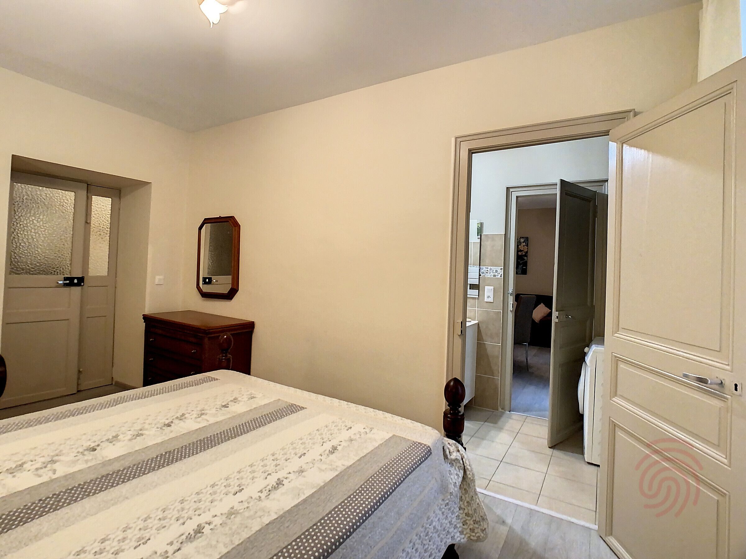 A bedroom with a bed, a dresser, a mirror, and a door leading to a bathroom.