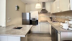 Eine moderne Küche mit integriertem Backofen, einem Edelstahl-Kühlschrank und einem Geschirrspüler.