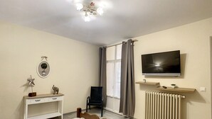 Ein Schlafzimmer mit einem Bett, einem Fernseher, einem Schreibtisch, einem Stuhl und einer Heizung.