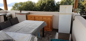 Un petit espace cuisine extérieur comprenant une table, un meuble en bois et un réfrigérateur.