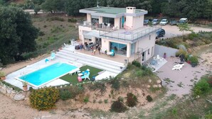 Een tweelaags huis met een zwembad, terras en tuin.