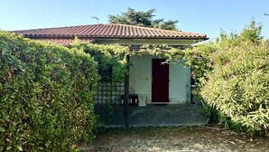 Un piccolo edificio con tetto in tegole, una porta rossa e un ingresso coperto.